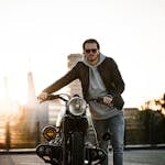 A man in casual wear stands by his motorcycle during sunset in Eindhoven.